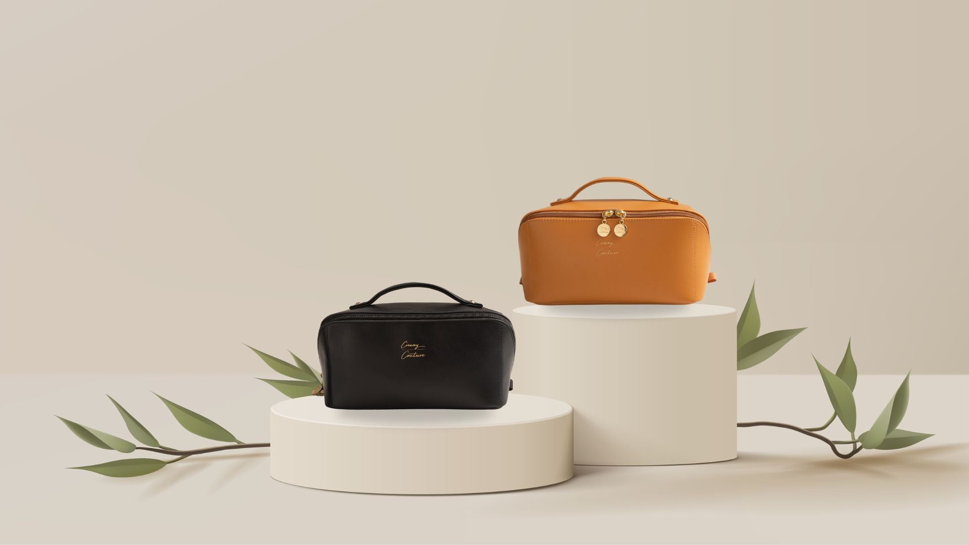 Two elegant Creamy Couture makeup bags, one in black and one in tan, displayed on minimalist round pedestals with decorative leaves.